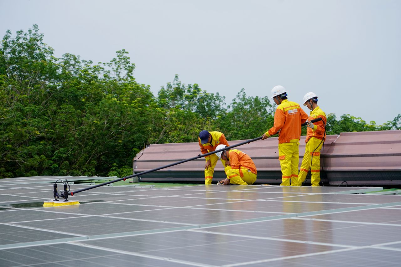 Home A team of workers cleaning solar panels on a sunny day, focusing on renewable energy maintenance.